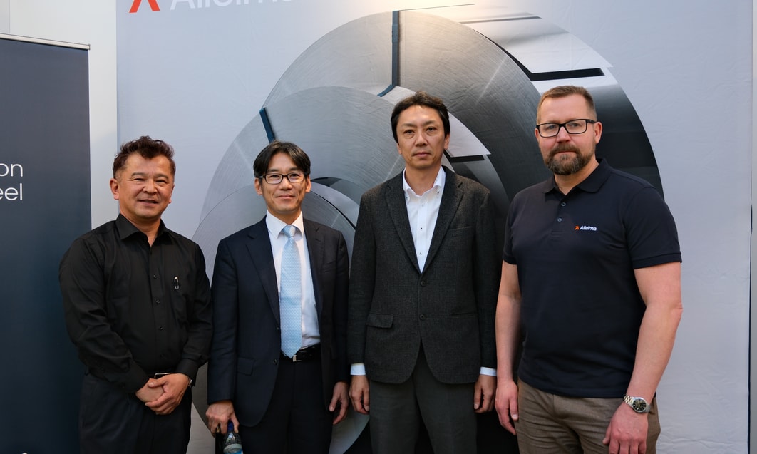a group of men standing in front of a wall with a logo