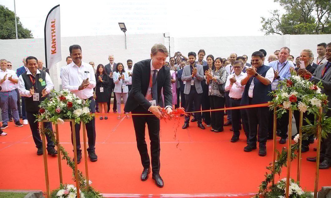 a person in a suit cutting a red ribbon