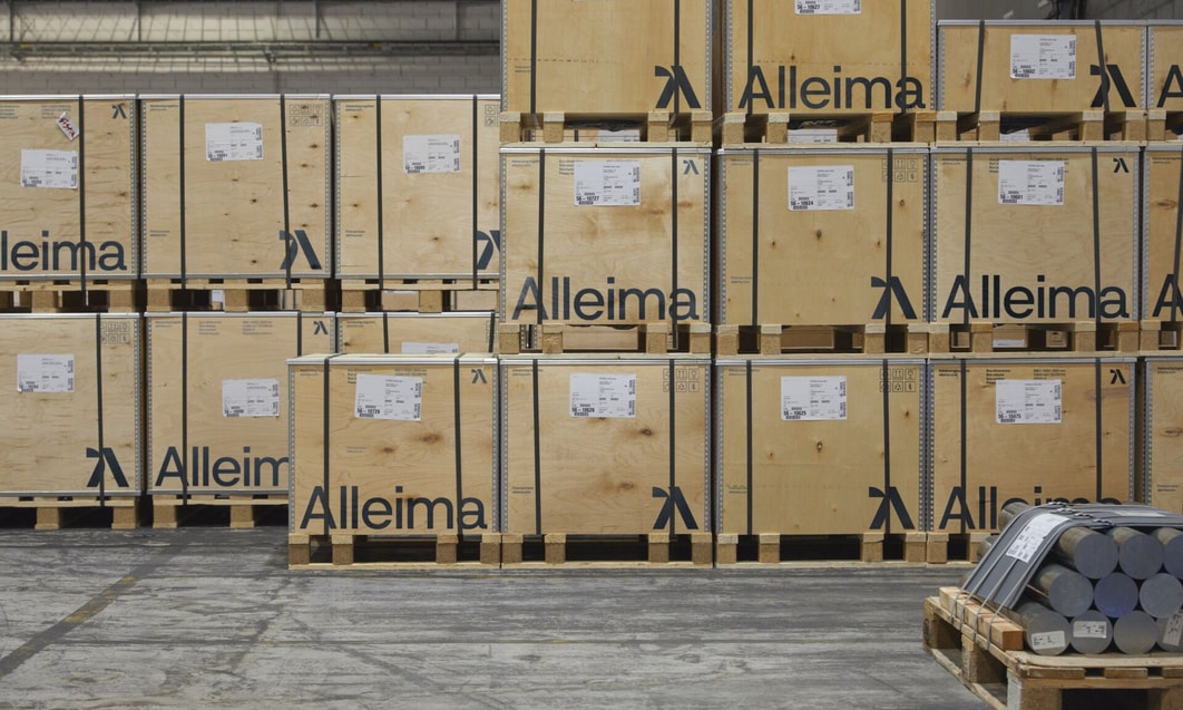 en lastpall med trä med en gaffeltruck framför sig