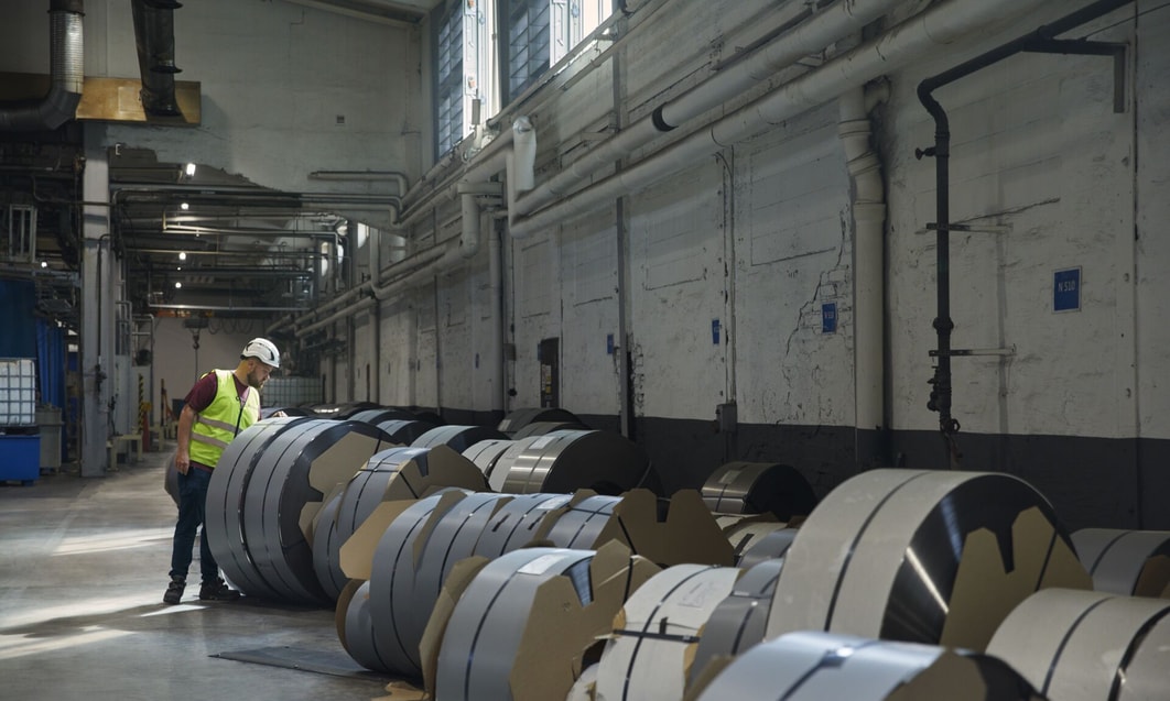 en person i en fabrik med stålrullar