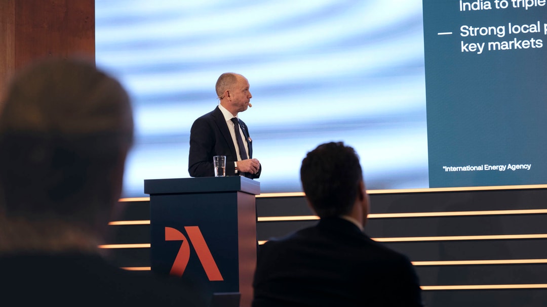 a person standing at a podium with a microphone and a screen behind him