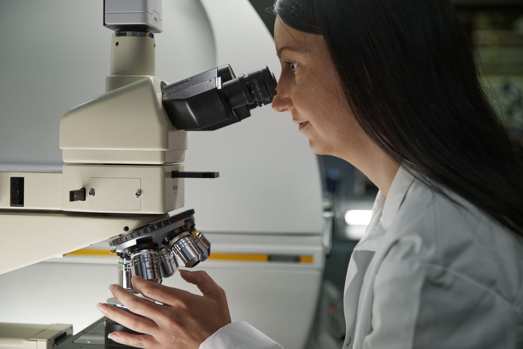 en person som tittar genom ett mikroskop