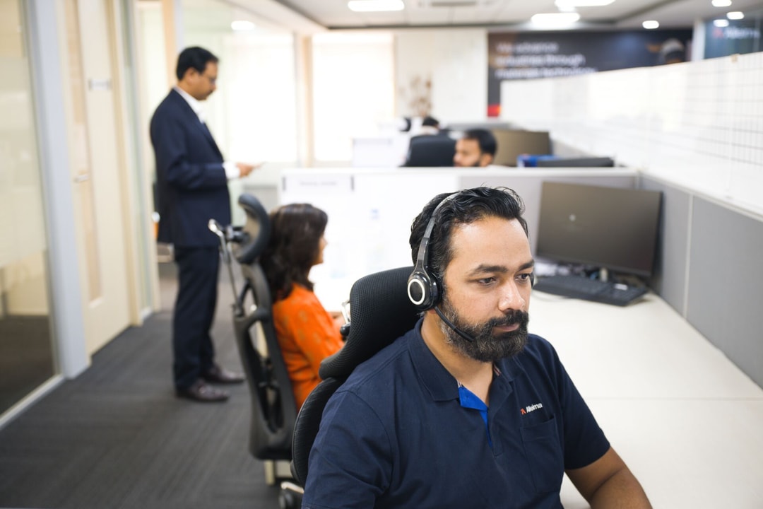 en person som bär headset och sitter på ett kontor