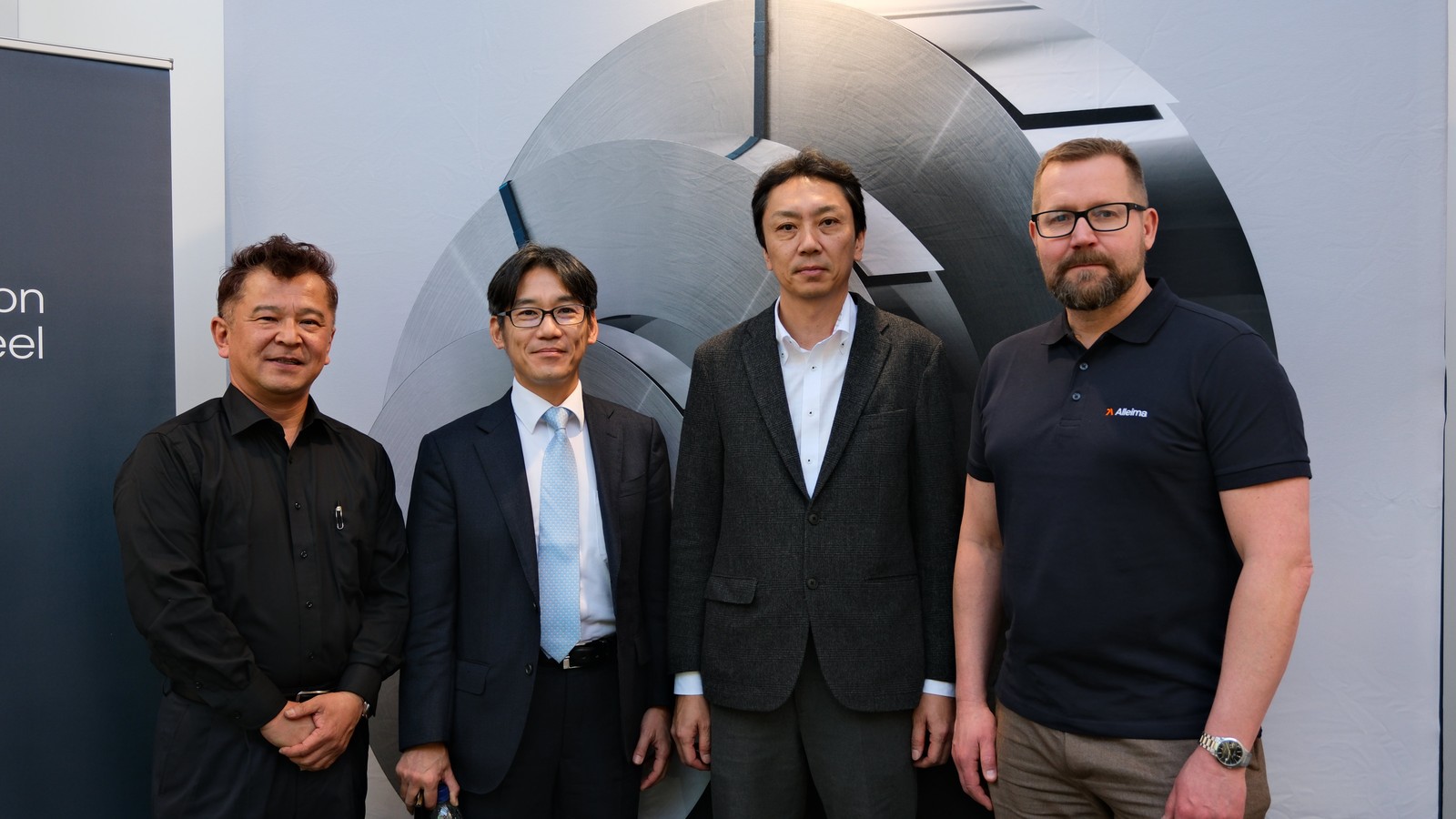 a group of men standing in front of a wall with a logo