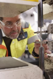 en person med skyddsglasögon och skyddsglasögon som arbetar på en maskin