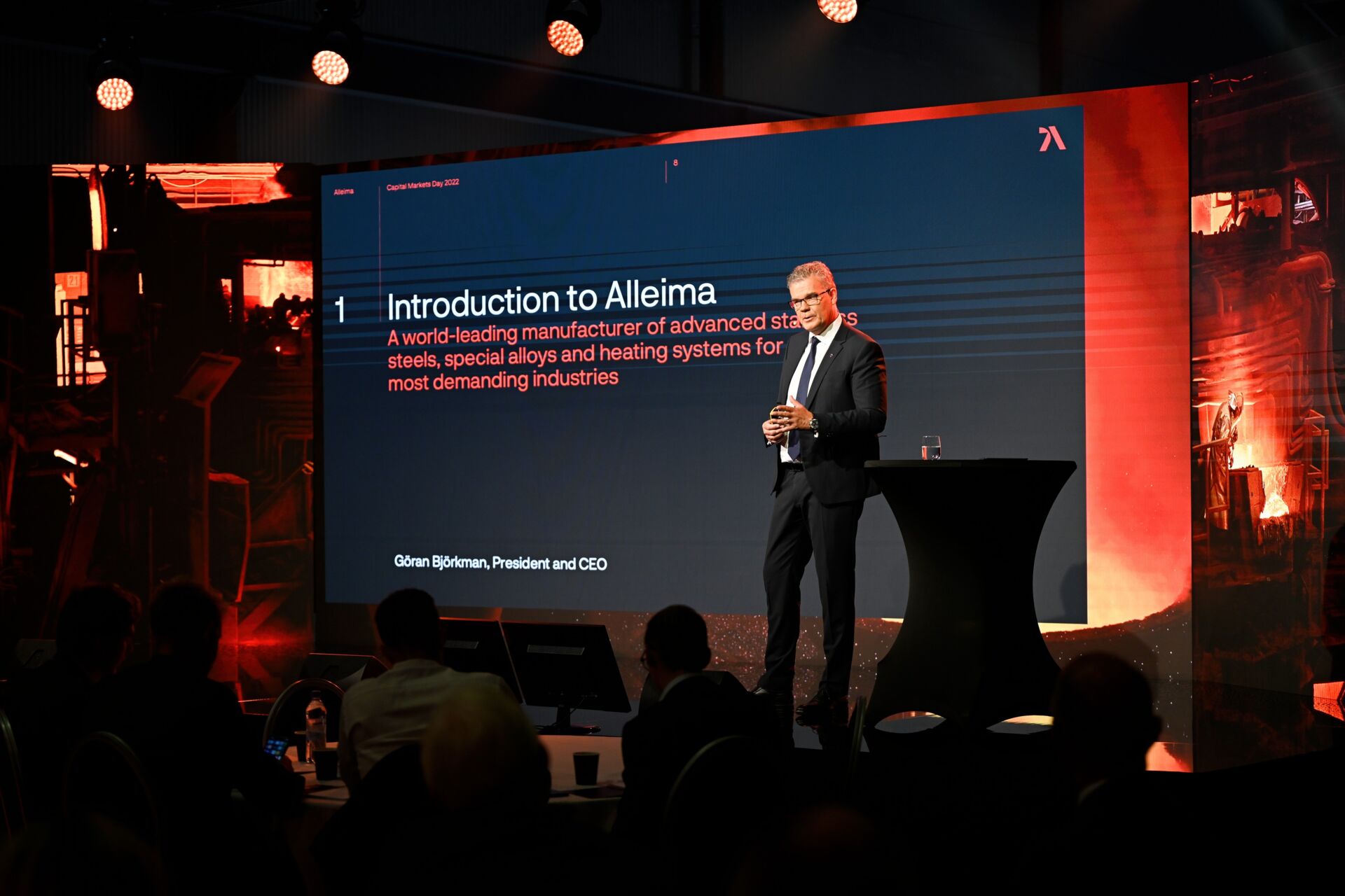 en person som står på ett podium med en stor skärm bakom sig