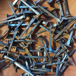 a pile of nails on a wood surface