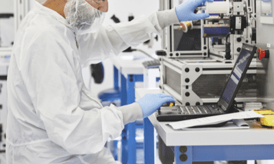 en person i vit kostym och handskar arbetar på en bärbar dator