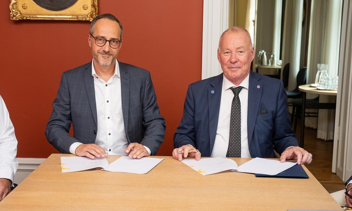 två män sitter vid ett bord med papper