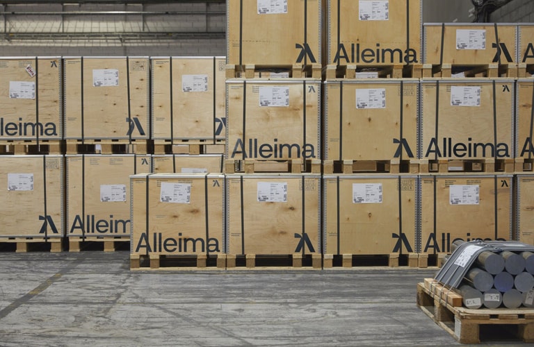 en lastpall med trä med en gaffeltruck framför sig