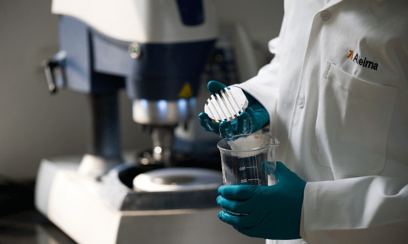 a person in a lab coat pouring liquid into a beaker
