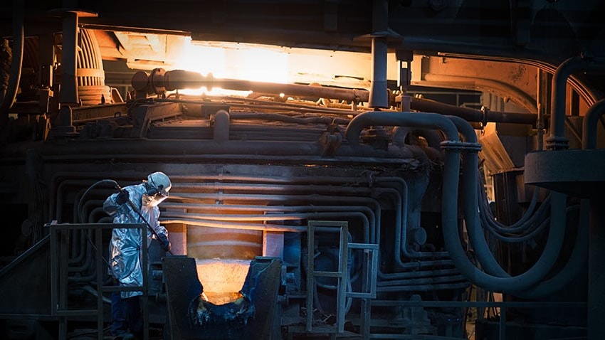 en person i vit kostym och mask som arbetar i en fabrik