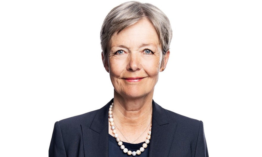 en person som bär en svart kostym och ett pärlhalsband