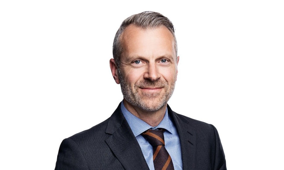 en person i kostym som ler